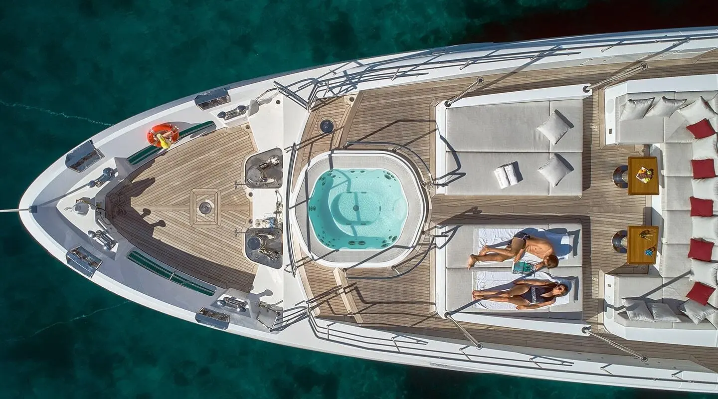 Aerial view of a luxury yacht named Happy Me at sunset, deck lounge and hot tub visible