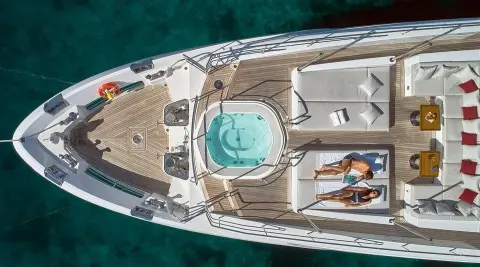Aerial view of a luxury yacht named Happy Me at sunset, deck lounge and hot tub visible