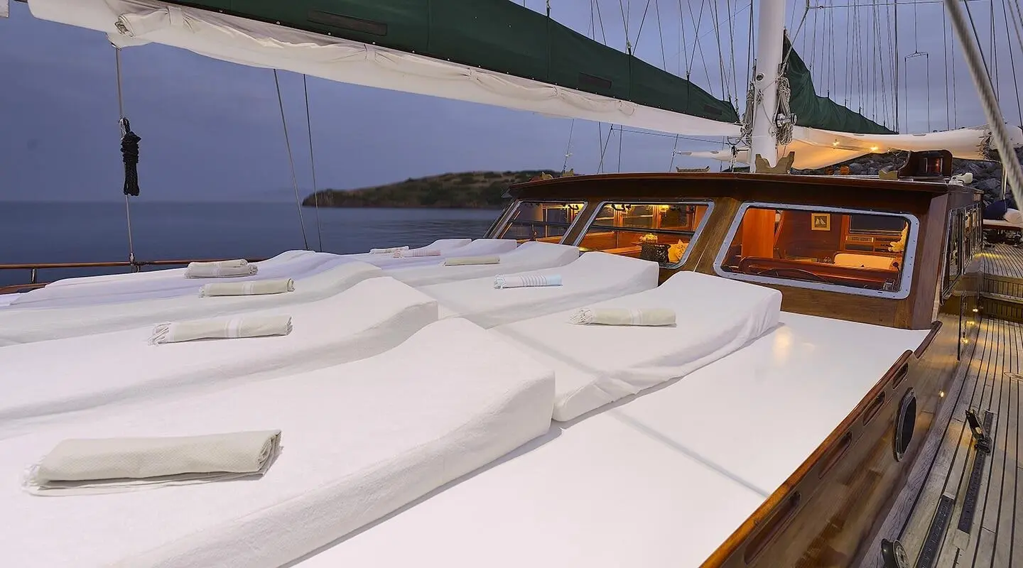 Ecce Navigo yacht charter: white deck loungers on a sailing yacht at sunset