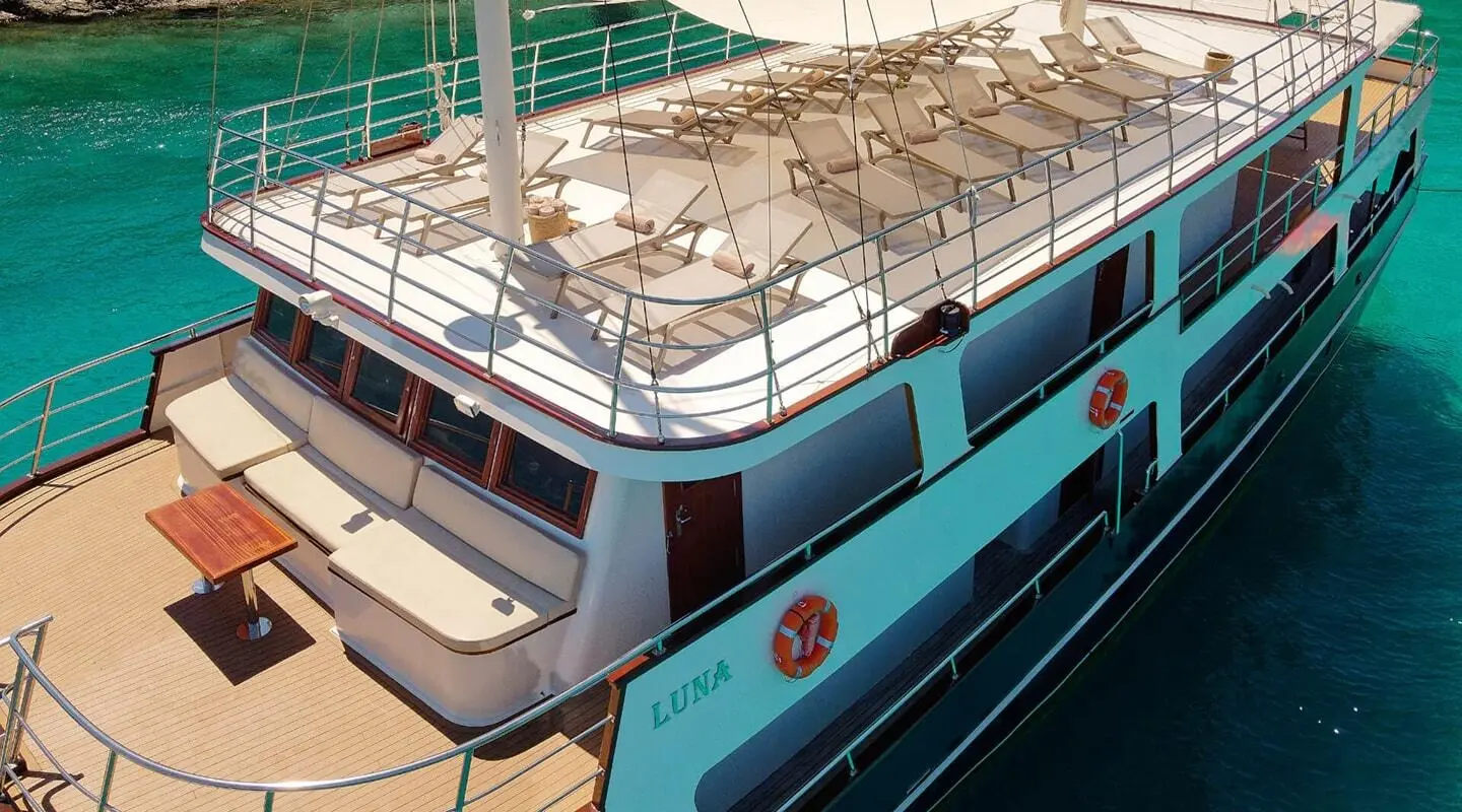 Luna motor yacht with sun loungers on upper deck, teal hull, exterior view