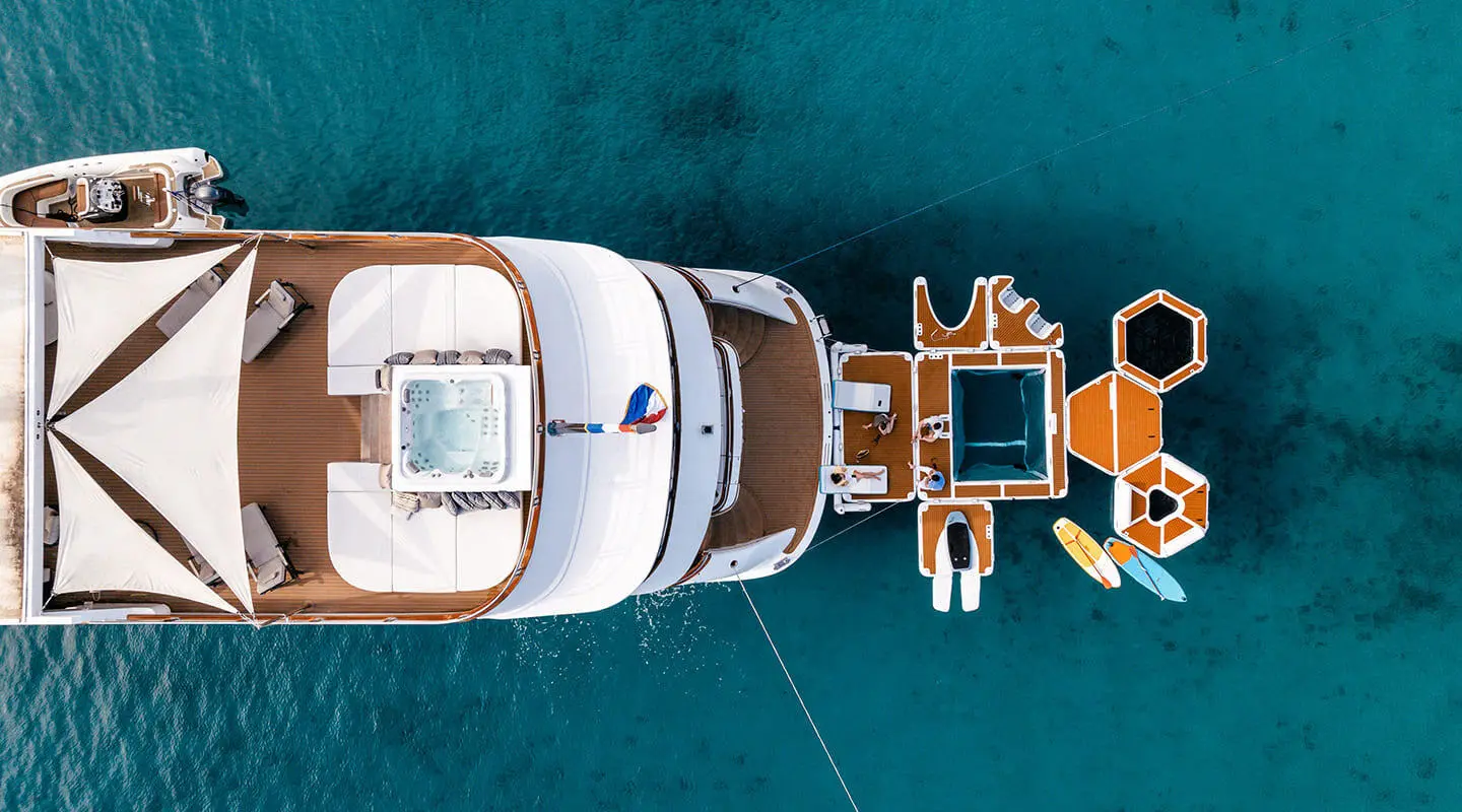 Top-down view of a white yacht named Cristal docked in blue water with a small dinghy nearby