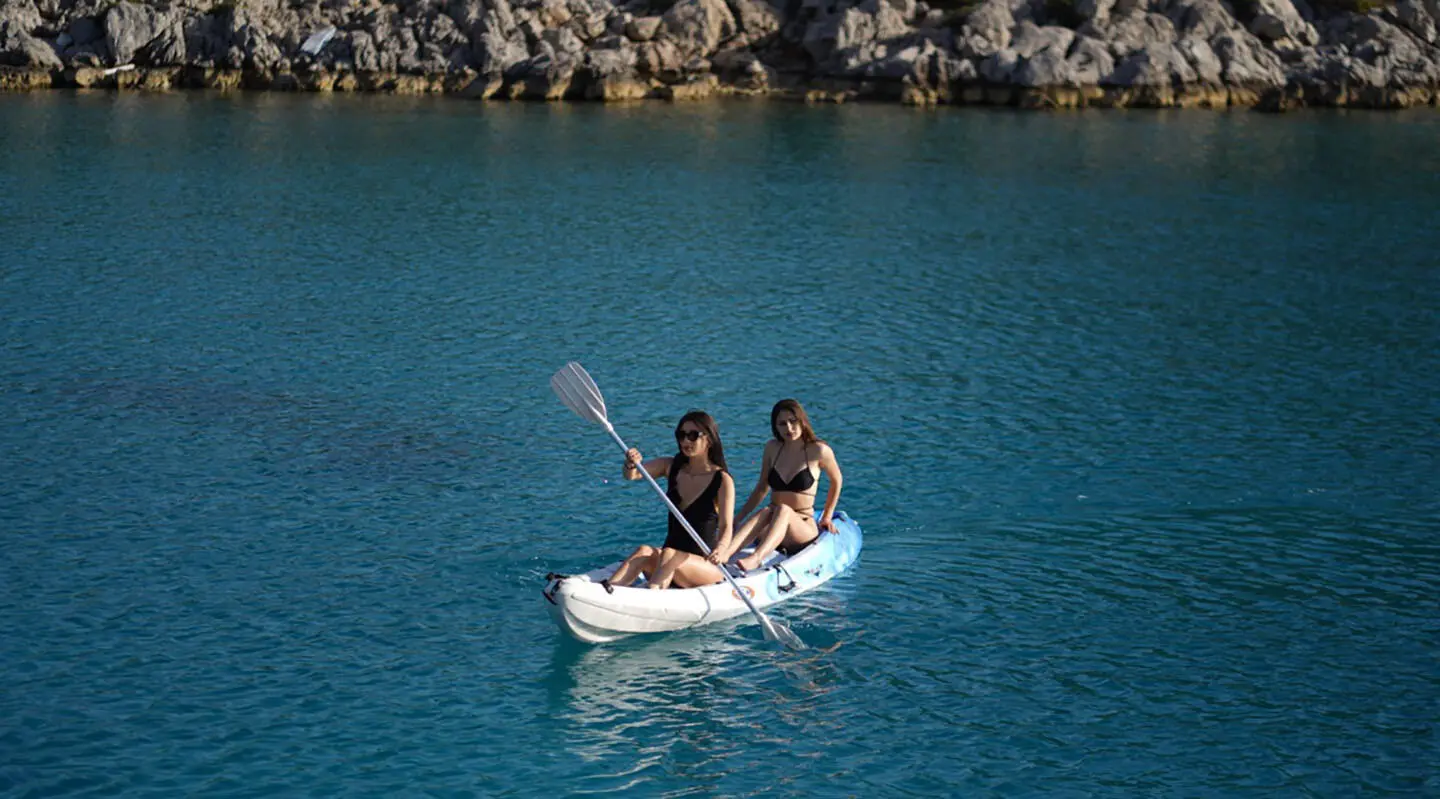 Prenses Esila yacht with two people in a small white boat on blue water at sunset
