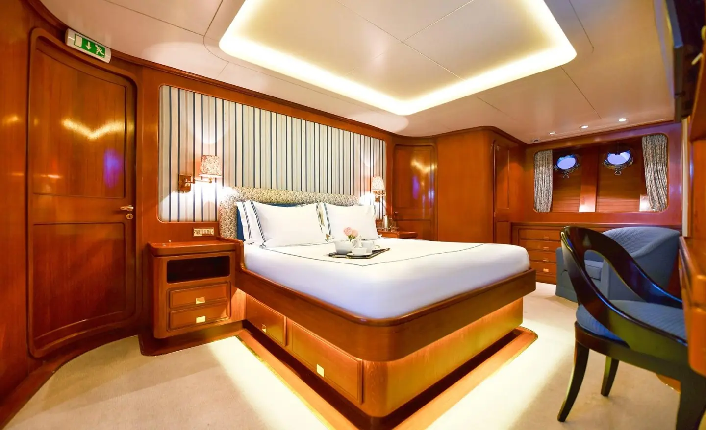 Tamarita luxury yacht interior with a large bed, polished wood, and warm lighting