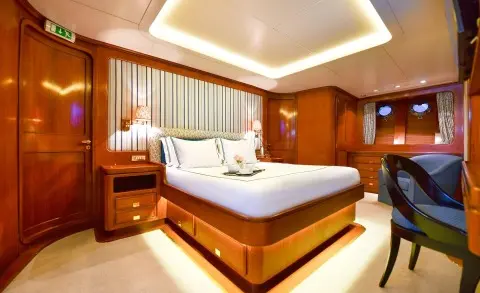Tamarita luxury yacht interior with a large bed, polished wood, and warm lighting