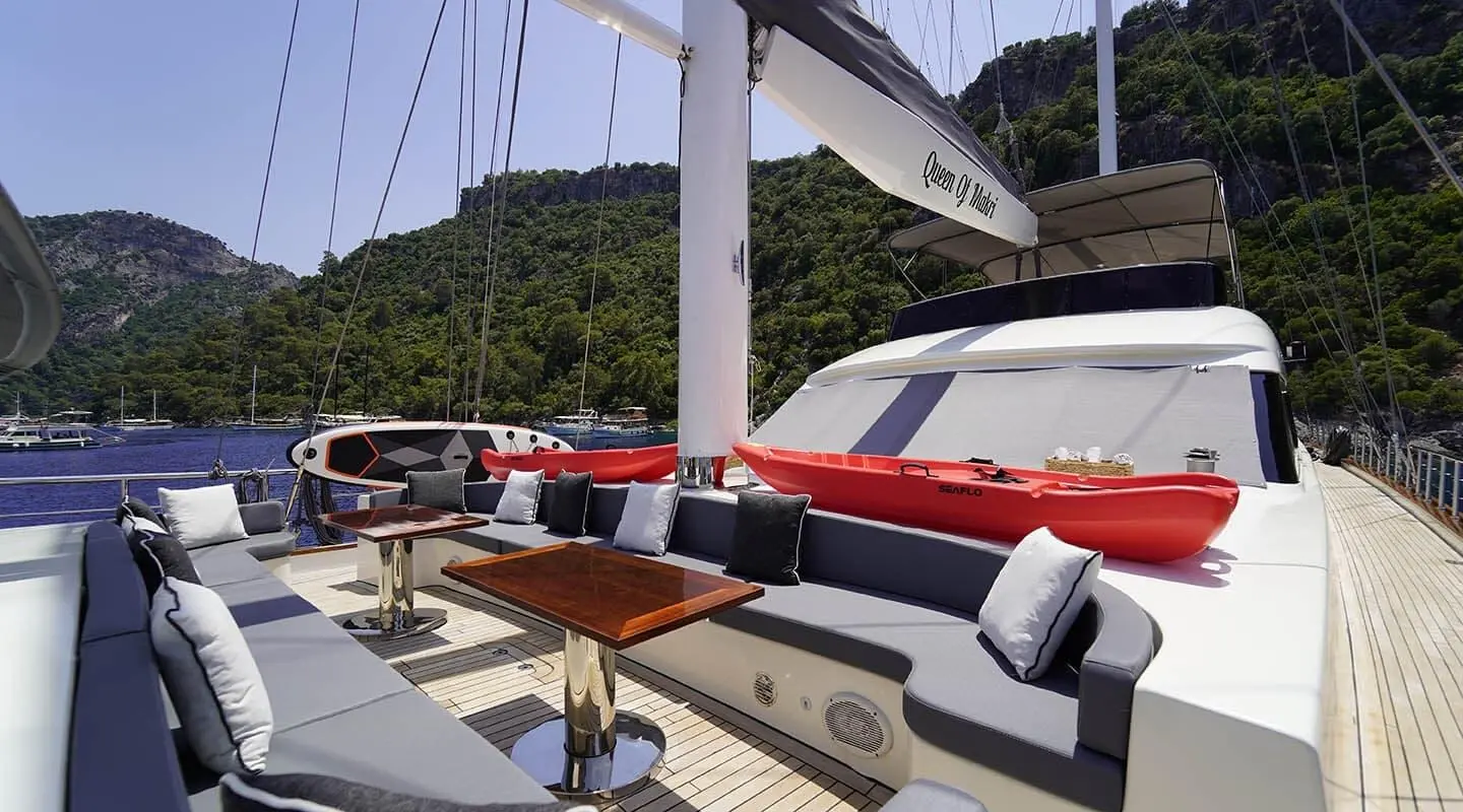 Queen Of Makri yacht deck with red and white seating at sunset on calm sea