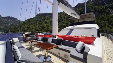 Queen Of Makri yacht deck with red and white seating at sunset on calm sea
