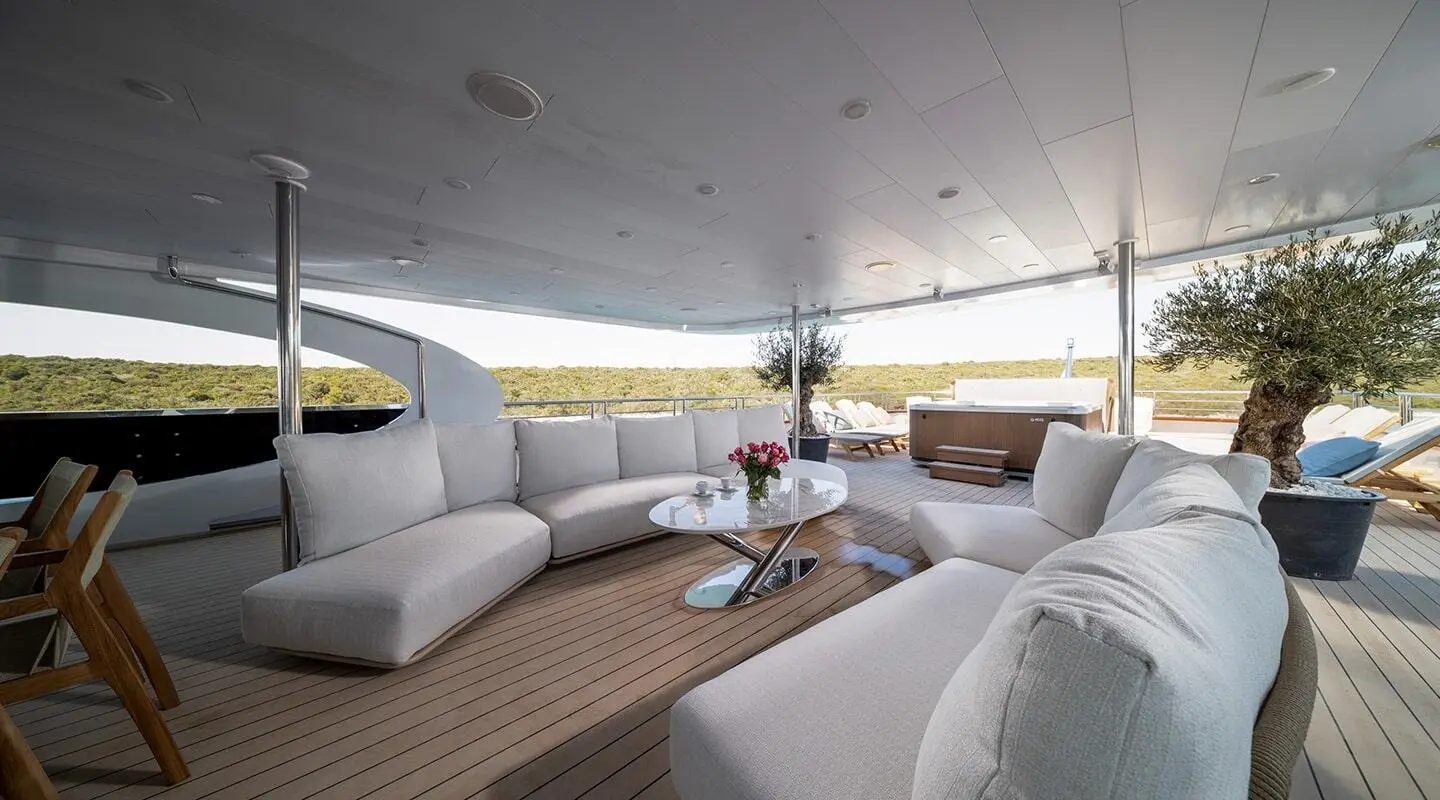 Lounge area of Olimp motor yacht with white seating under shaded deck