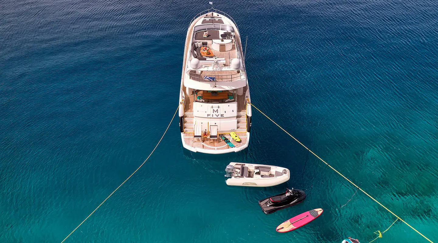 Aerial view of M Five yacht anchored in turquoise water with smaller dinghies nearby
