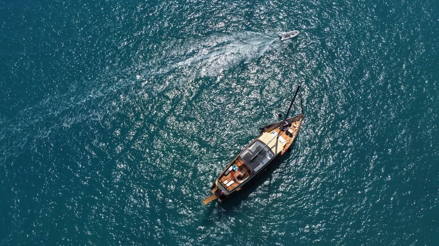 Small motor yacht Santa Clara gliding on blue sea, aerial view
