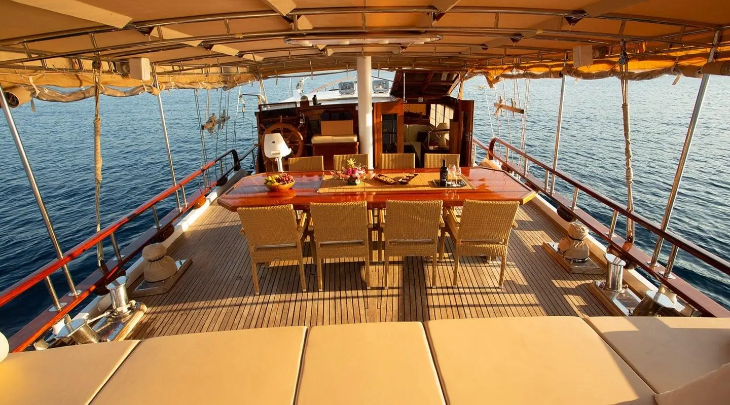 Malena yacht aft deck with seating, ropes, and sunlit marina backdrop