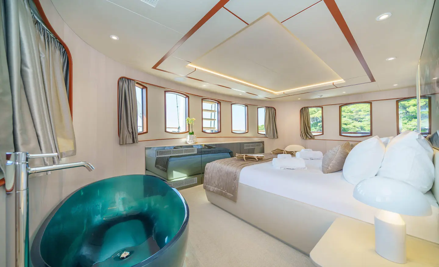 Maia yacht cabin with large bed, teal freestanding tub, and panoramic windows