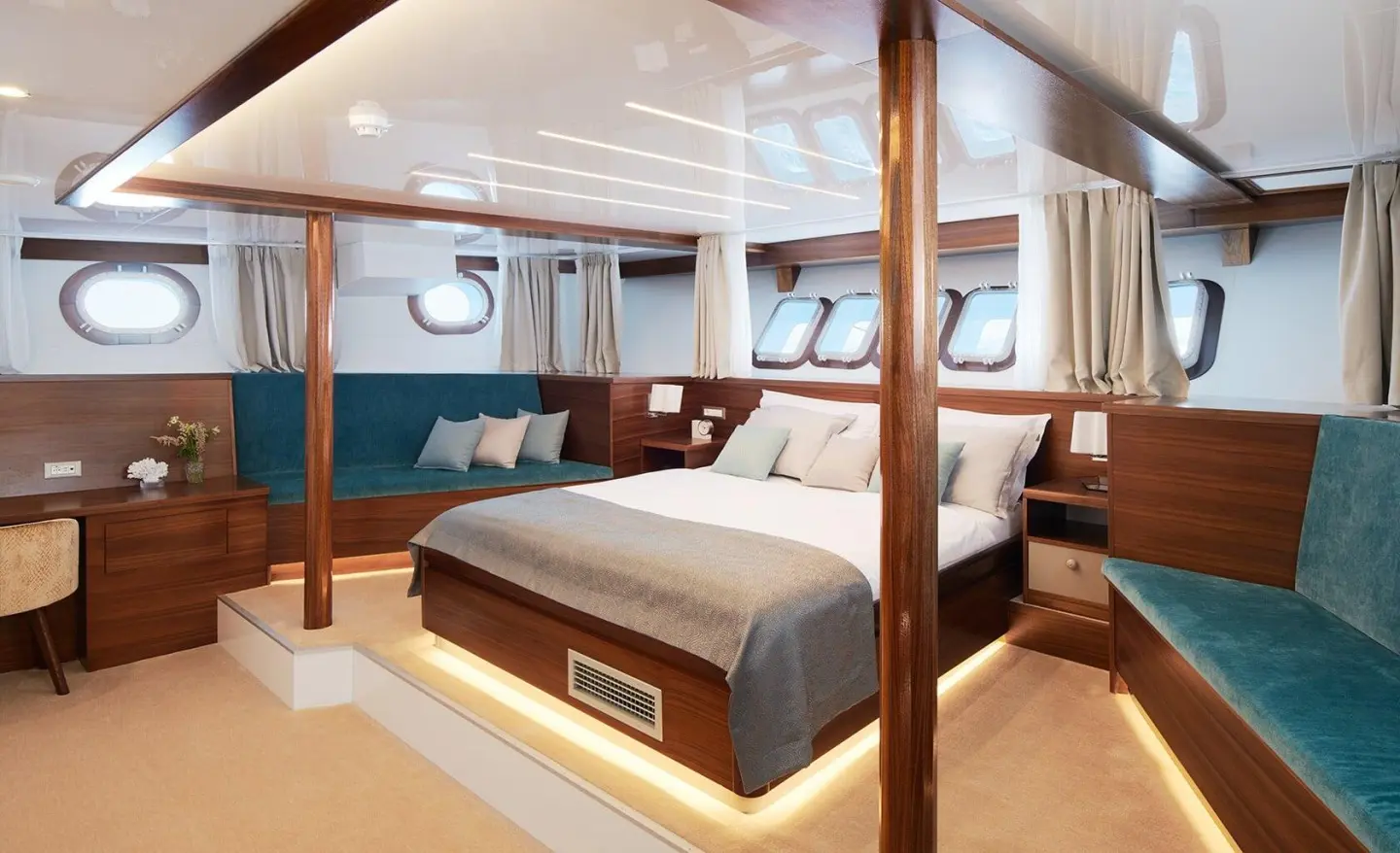 Luxurious yacht cabin with a wide bed, polished wood, and warm lighting
