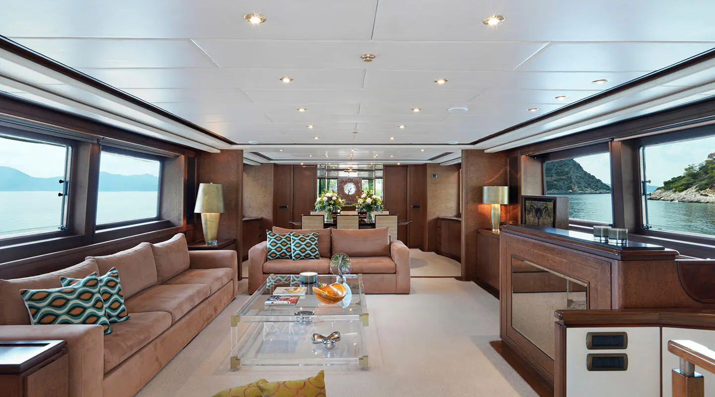 Luxurious yacht Idylle saloon interior with seating, coffee table, and warm lighting