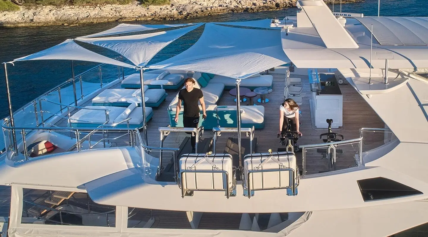 Happy Me yacht on a sun deck with blue-and-white striped awning and seating