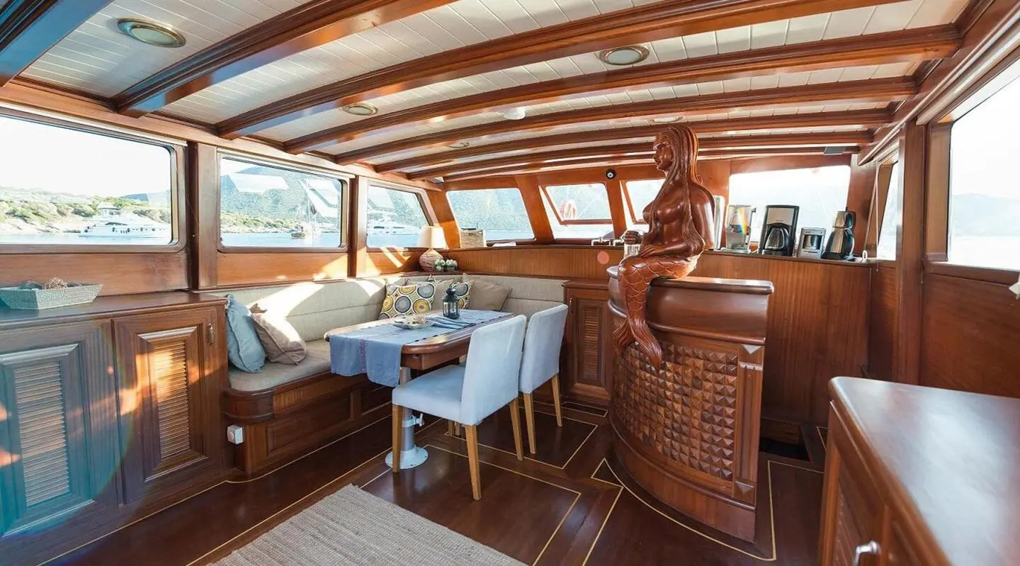 Inside Primadonna yacht: polished wood deck, seating area, and helm at sunset