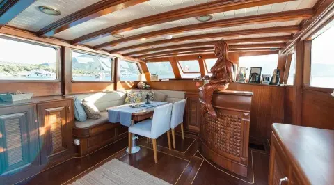 Inside Primadonna yacht: polished wood deck, seating area, and helm at sunset