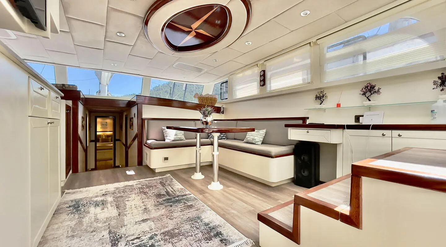 Luxurious yacht interior with dining area, seating, and large windows at sunset