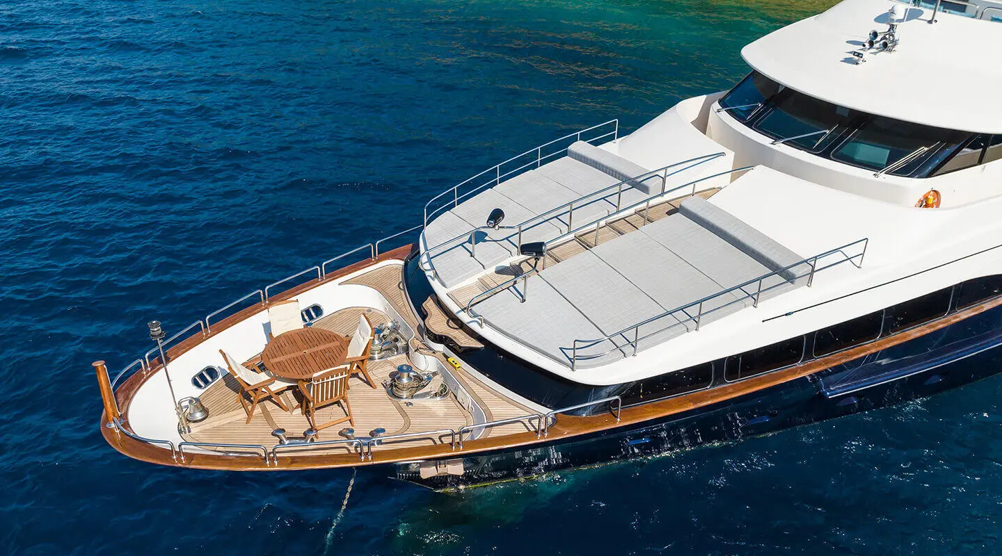 Amadea yacht stern deck with sun loungers and dining table on a clear blue sea