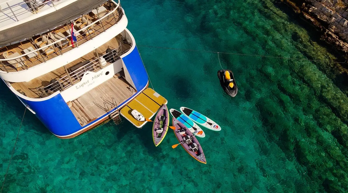 Overhead view of Lupus Mare yacht docked in turquoise water with inflatable dinghies nearby