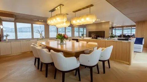 Scorpios luxury yacht dining salon with long light wood table and white upholstered chairs