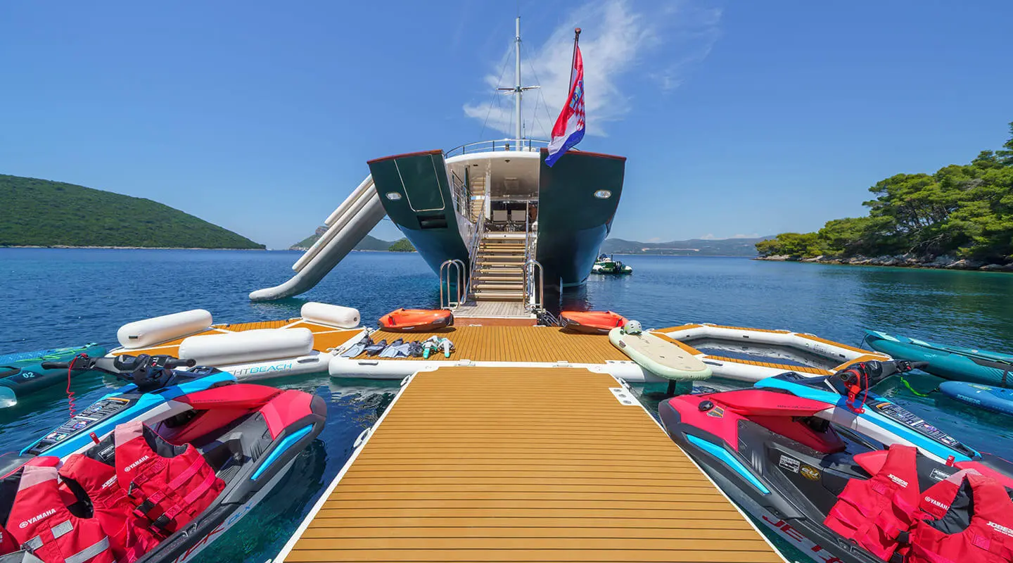 View from a marina dock toward Maia yacht stern, gangway extending ahead