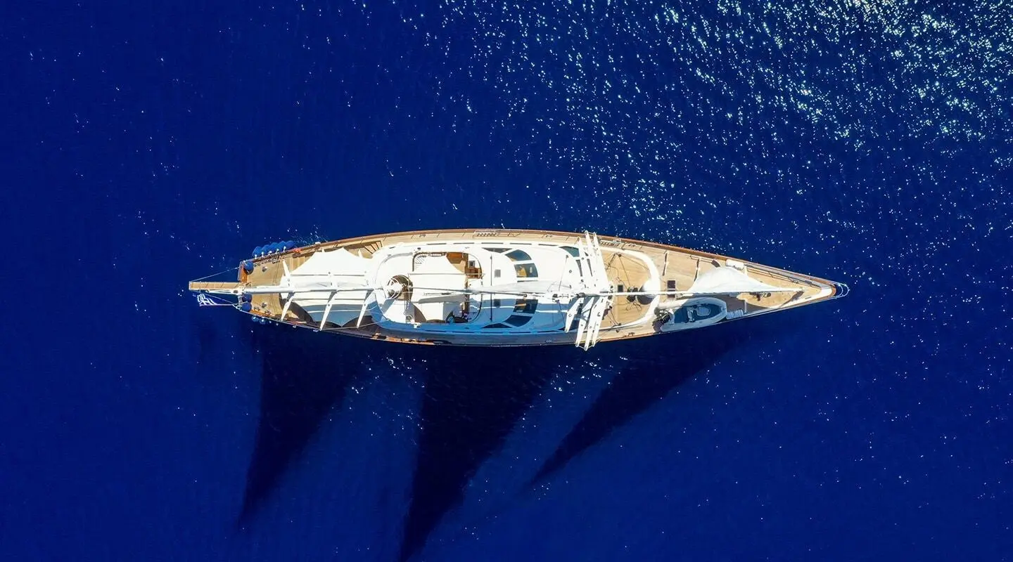 Aerial view of Tamarita sailing yacht with sunlit deck over deep blue sea