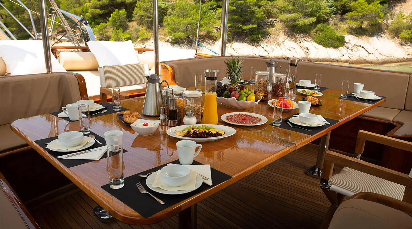 Dolce Vita yacht on calm sunset harbor with dining table set and rigging visible