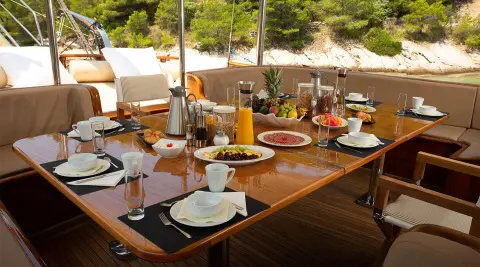 Dolce Vita yacht on calm sunset harbor with dining table set and rigging visible