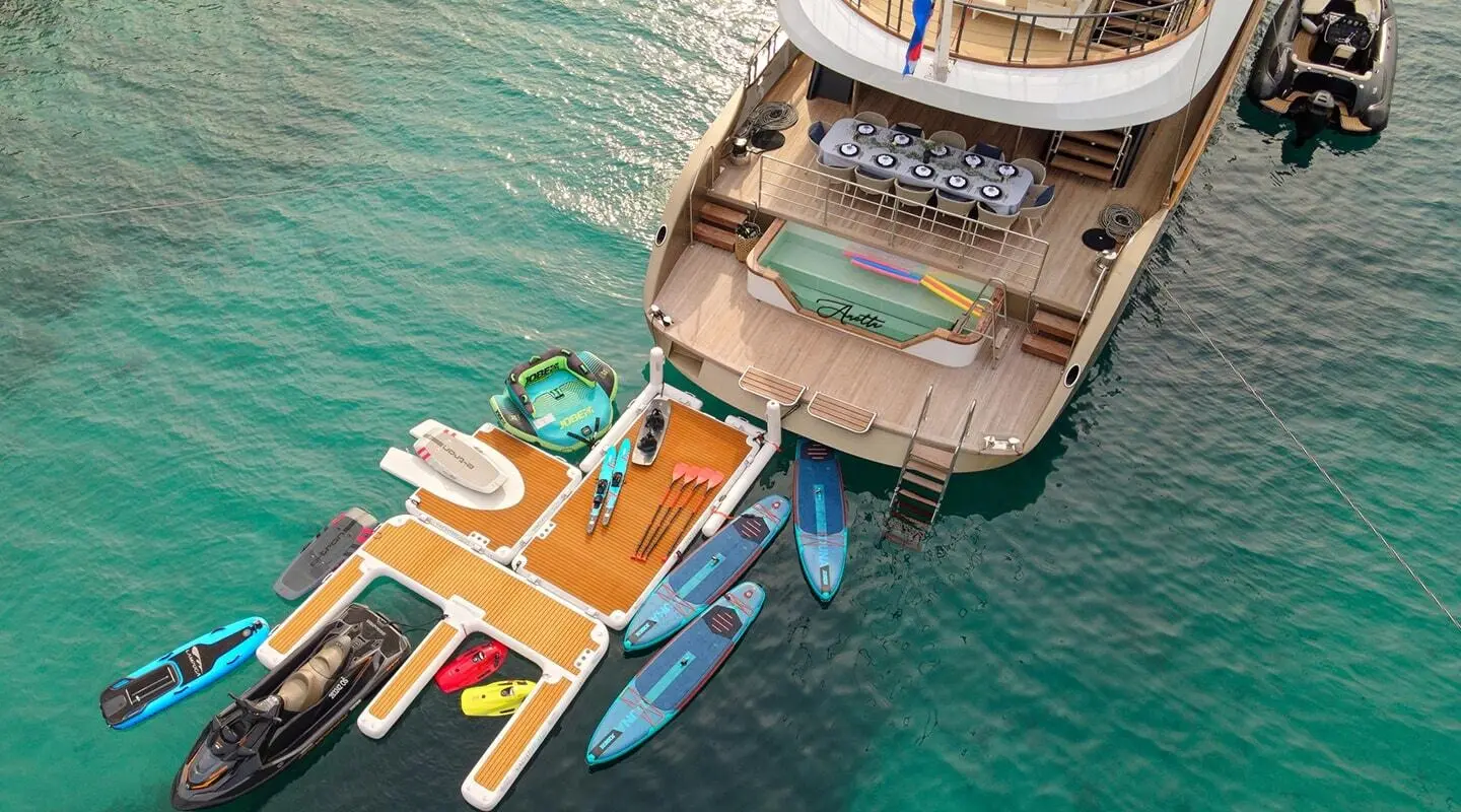 Top-down view of luxury yacht Anetta docked alongside smaller boats in turquoise harbor