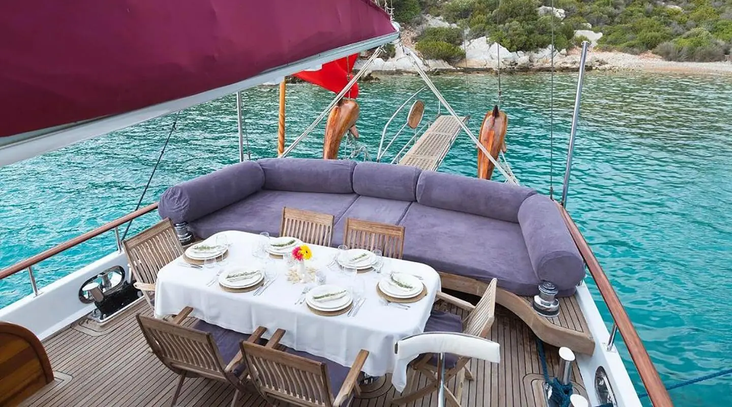 Gulet Primadonna aft deck seating and table setup overlooking turquoise sea