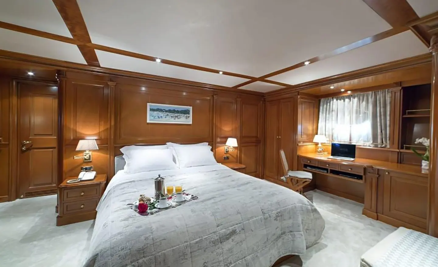 Aquila luxury yacht cabin with wood paneling, king bed, and workspace