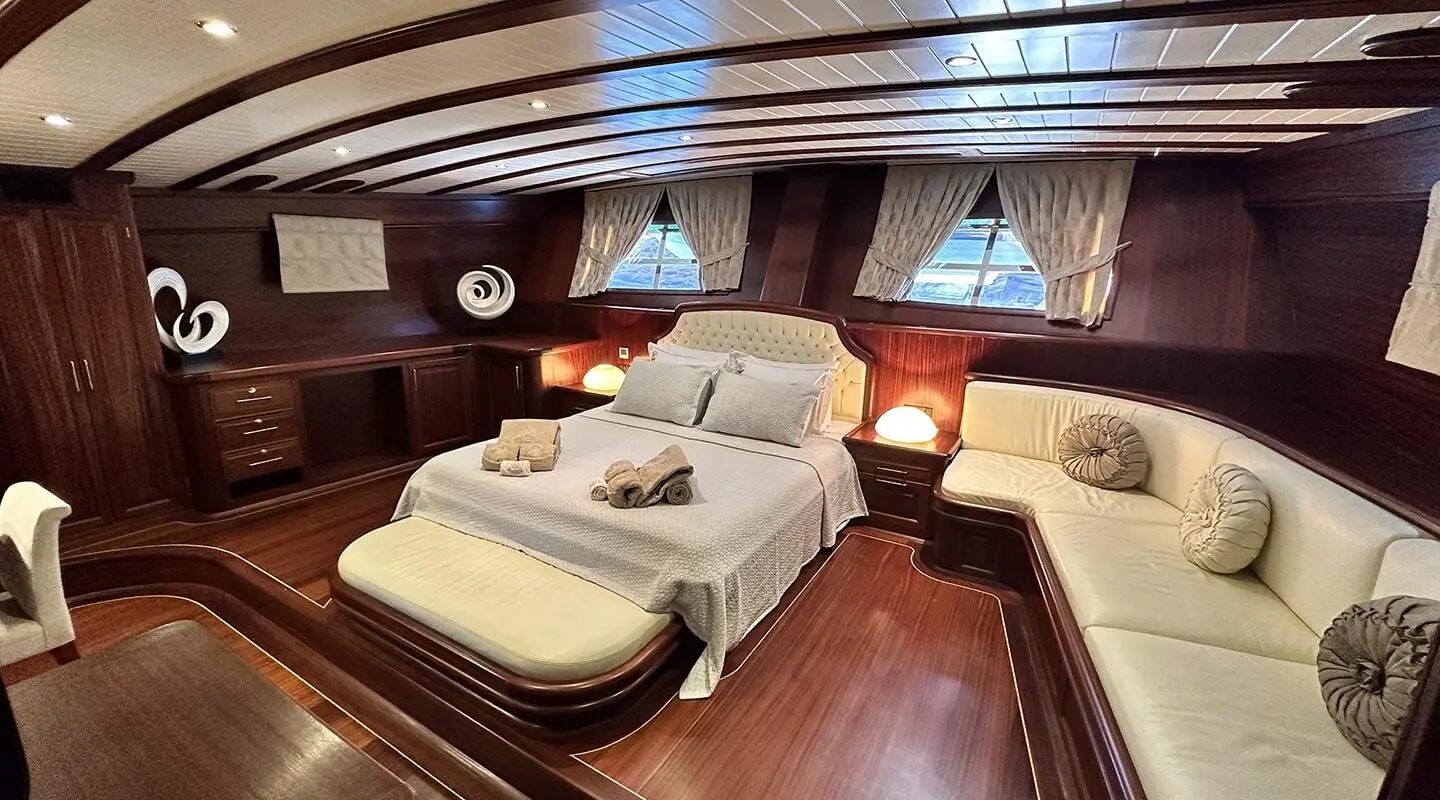Interior shot of Arif Kaptan A yacht with a large bed, wood floors, and porthole windows