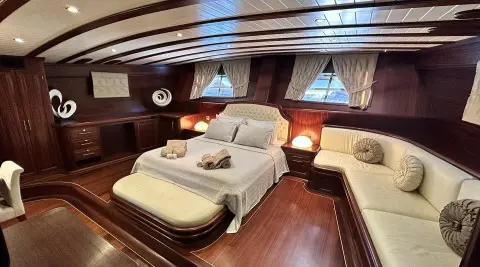 Interior shot of Arif Kaptan A yacht with a large bed, wood floors, and porthole windows