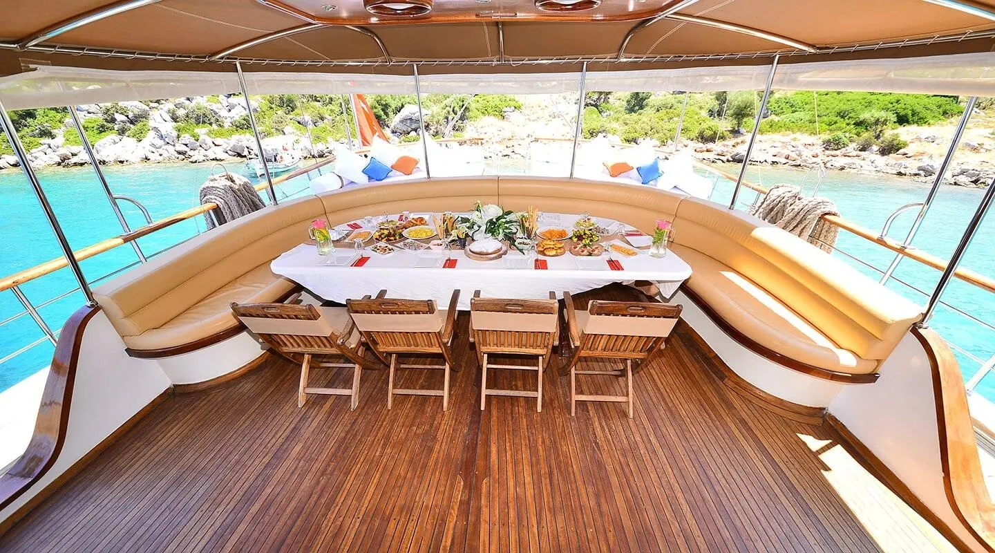 Prenses Bugce yacht dining area with a curved wooden table and chairs under a shaded deck