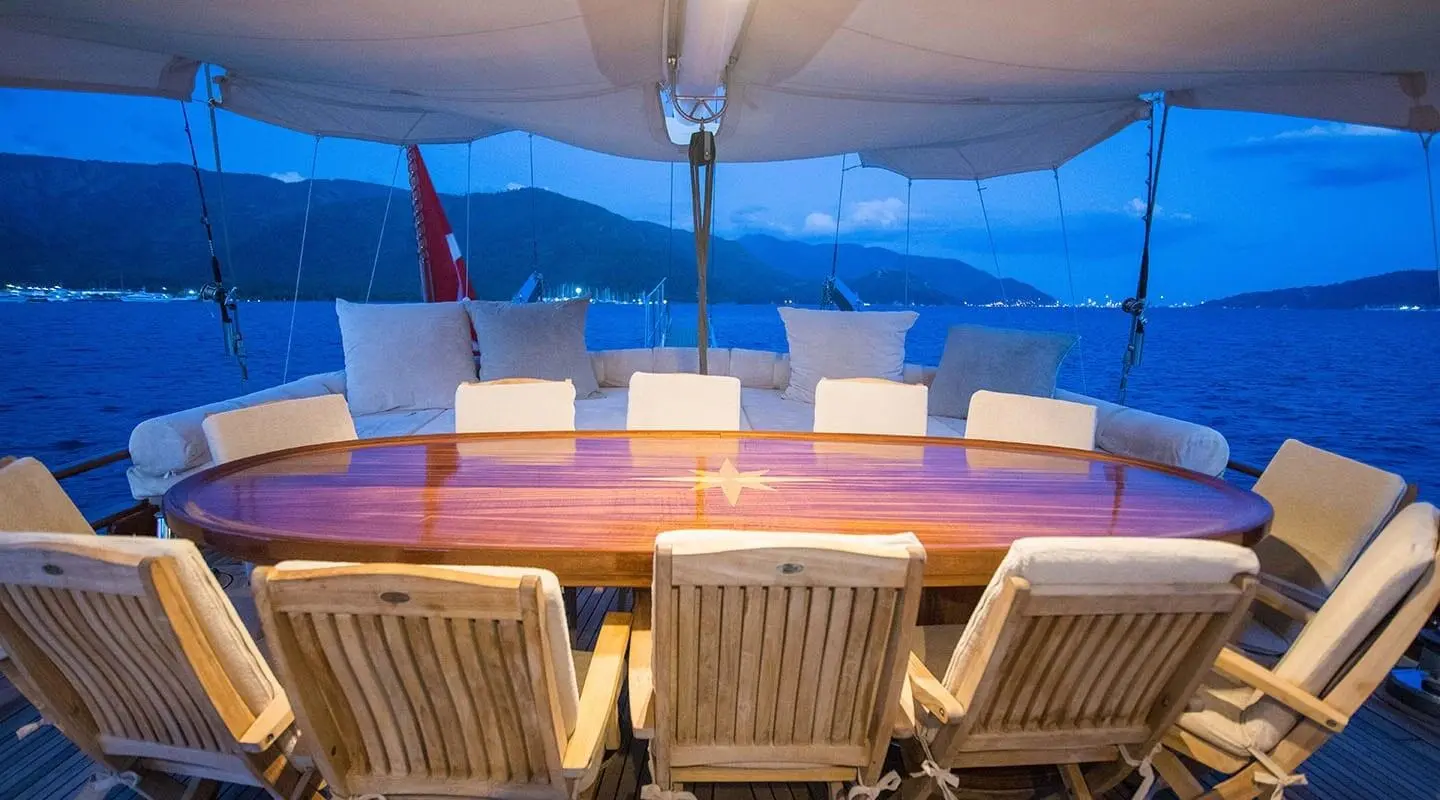 Gulet Grande Mare dining area on aft deck with cushioned seating and sun loungers under blue shade