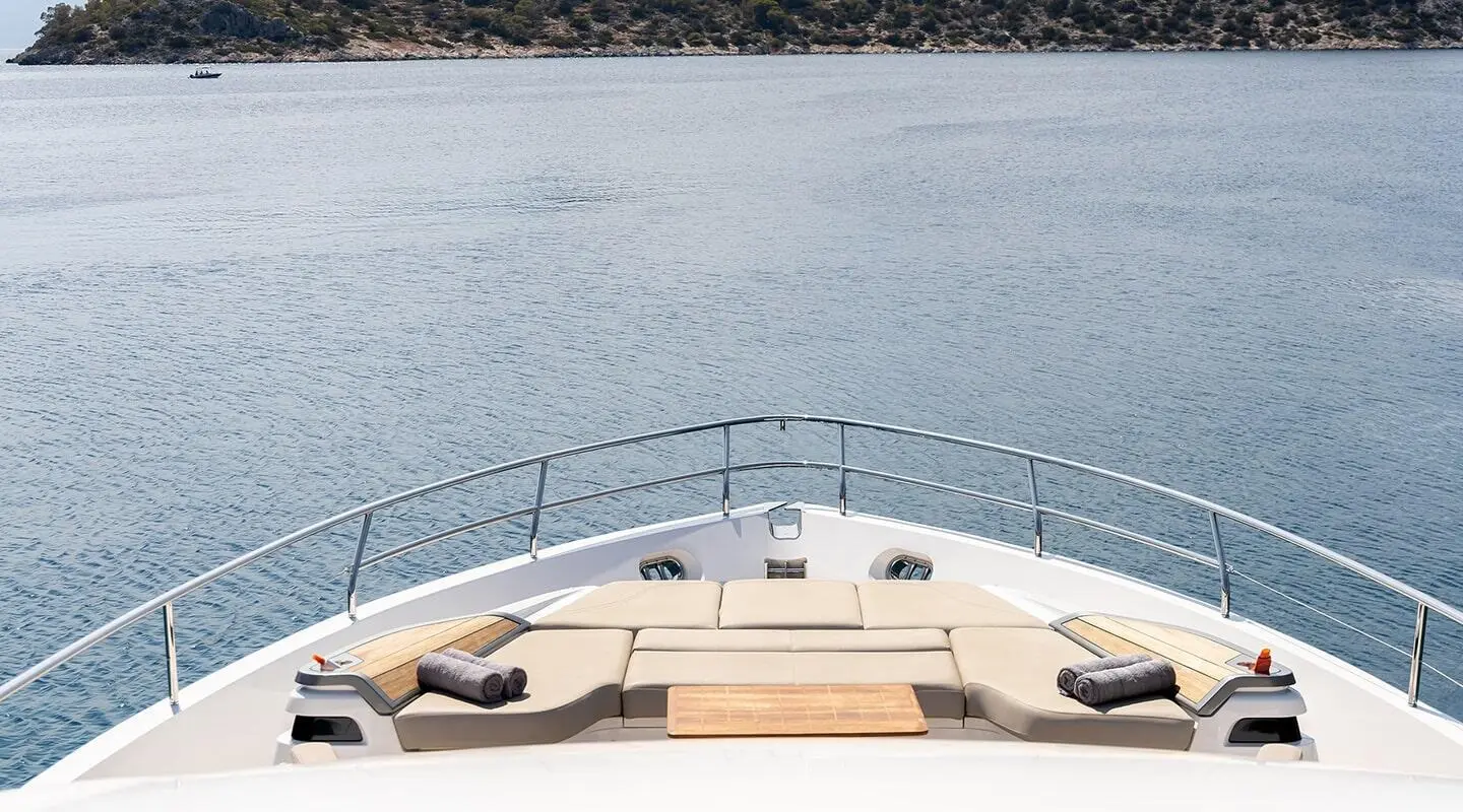 Vista luxury yacht bow sun loungers and teak table on deck overlooking calm blue sea