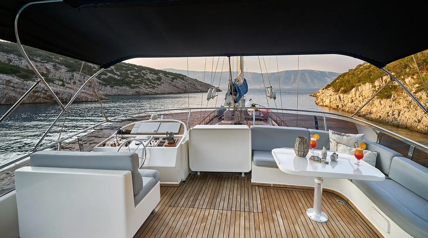 Yacht Lotus flybridge with seating, railing, and blue water backdrop