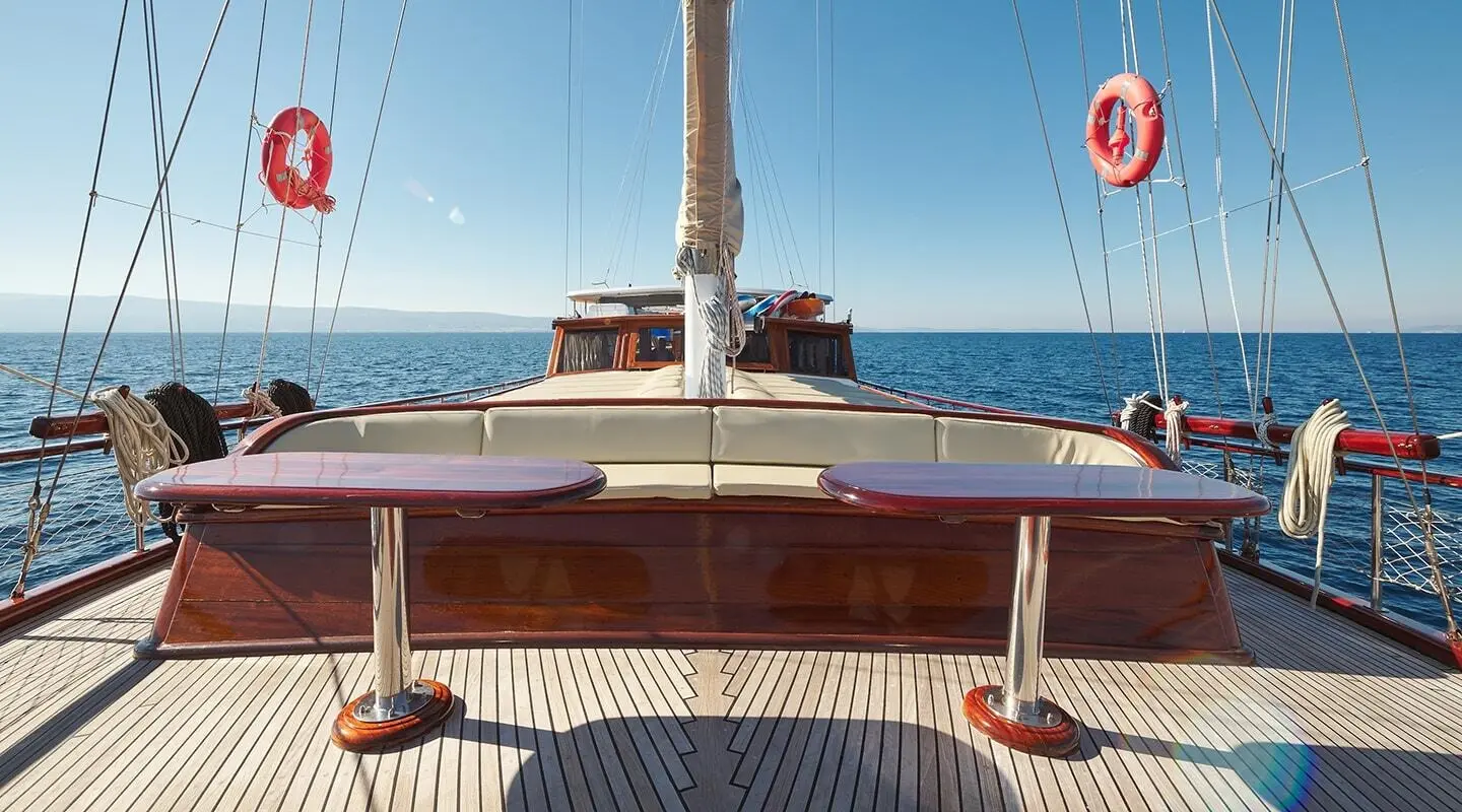 Linda yacht leaving a harbor at sunset with a wooden deck and ropes