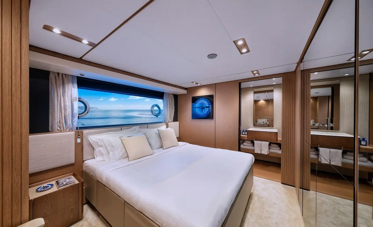 Spica yacht cabin with large bed, windows, and warm wood interior