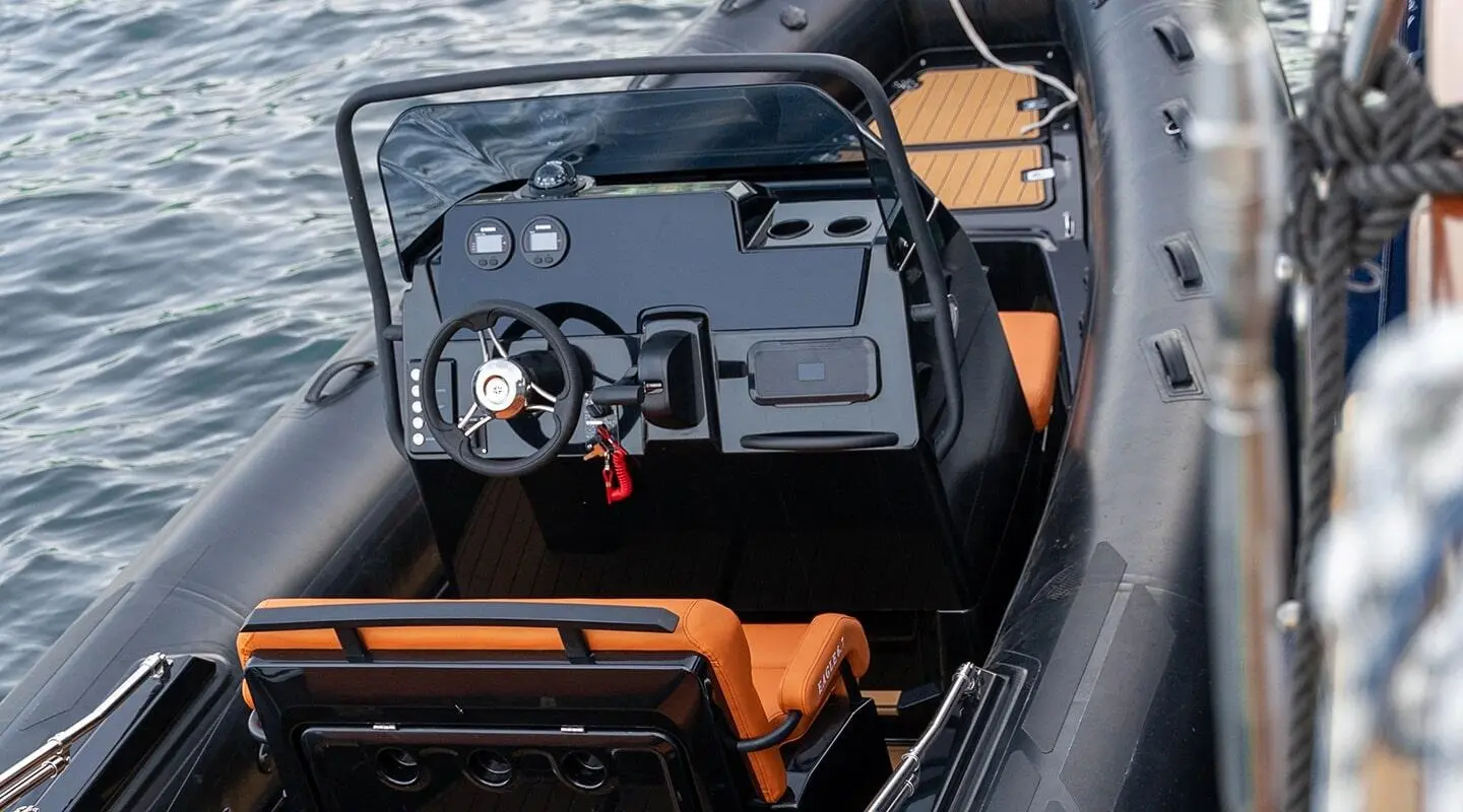 Top-down cockpit view of a yacht helm with steering wheel and navigation gear