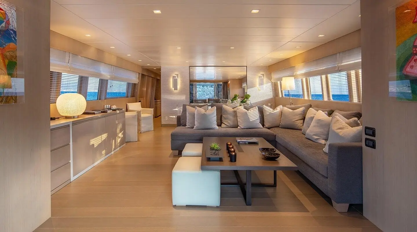 Interior of a yacht salon with seating, table, and wood flooring
