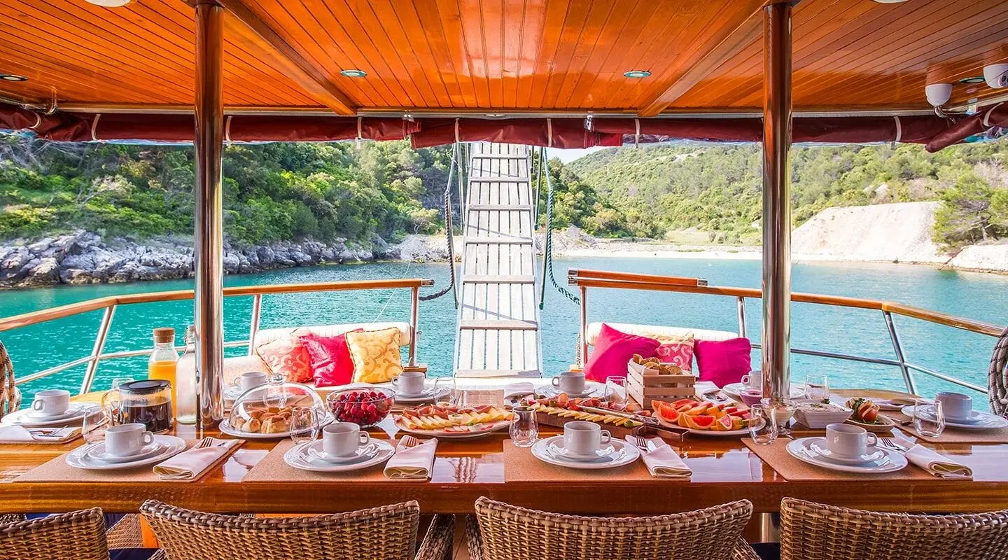 Altair yacht deck set for sunset dining with red cushions and tableware