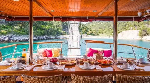 Altair yacht deck set for sunset dining with red cushions and tableware