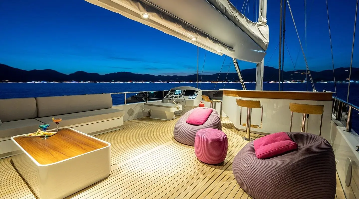 Yacht Good Life deck shown with pink and beige seating under a sail at sunset