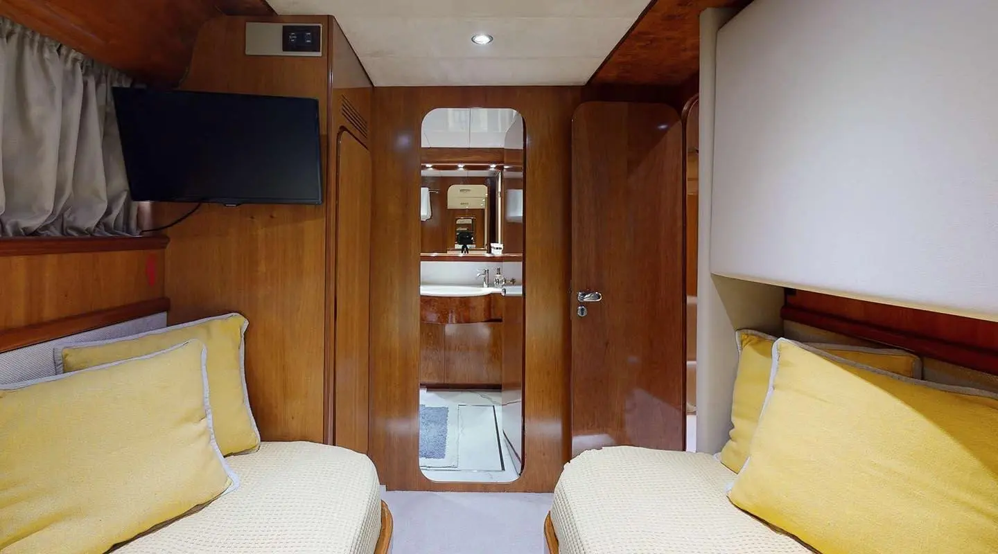 Interior of Lady Natassa motor yacht: twin cabin with wood panels and yellow cushions