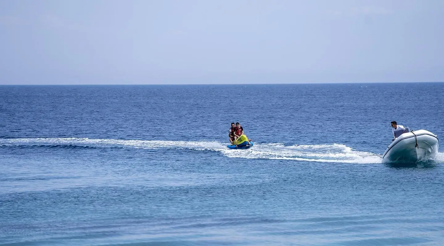 Two people on a jet ski being towed by a motor boat on the sea