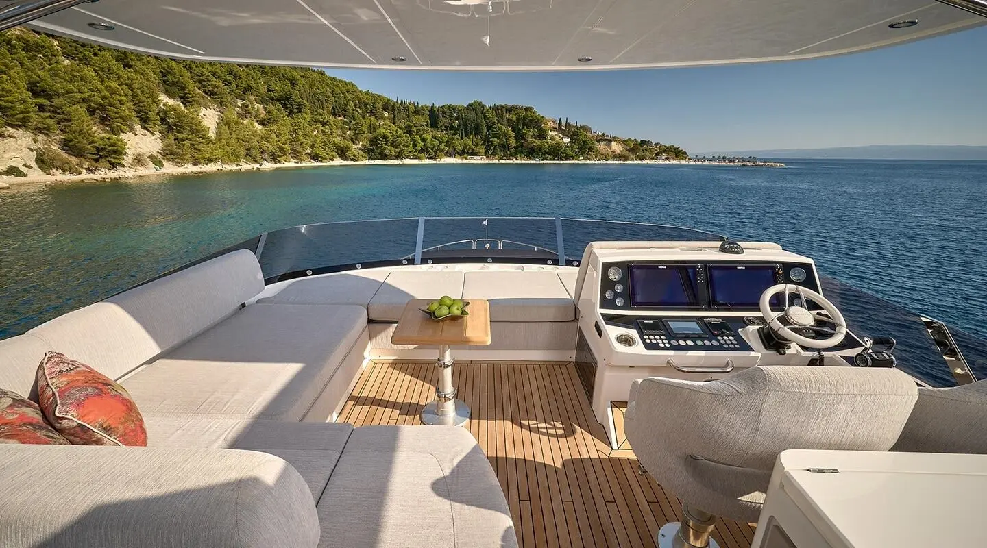 View from yacht deck toward sunlit sea, modern lounge seating and wooden deck
