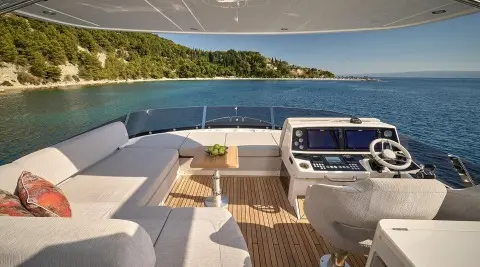 View from yacht deck toward sunlit sea, modern lounge seating and wooden deck