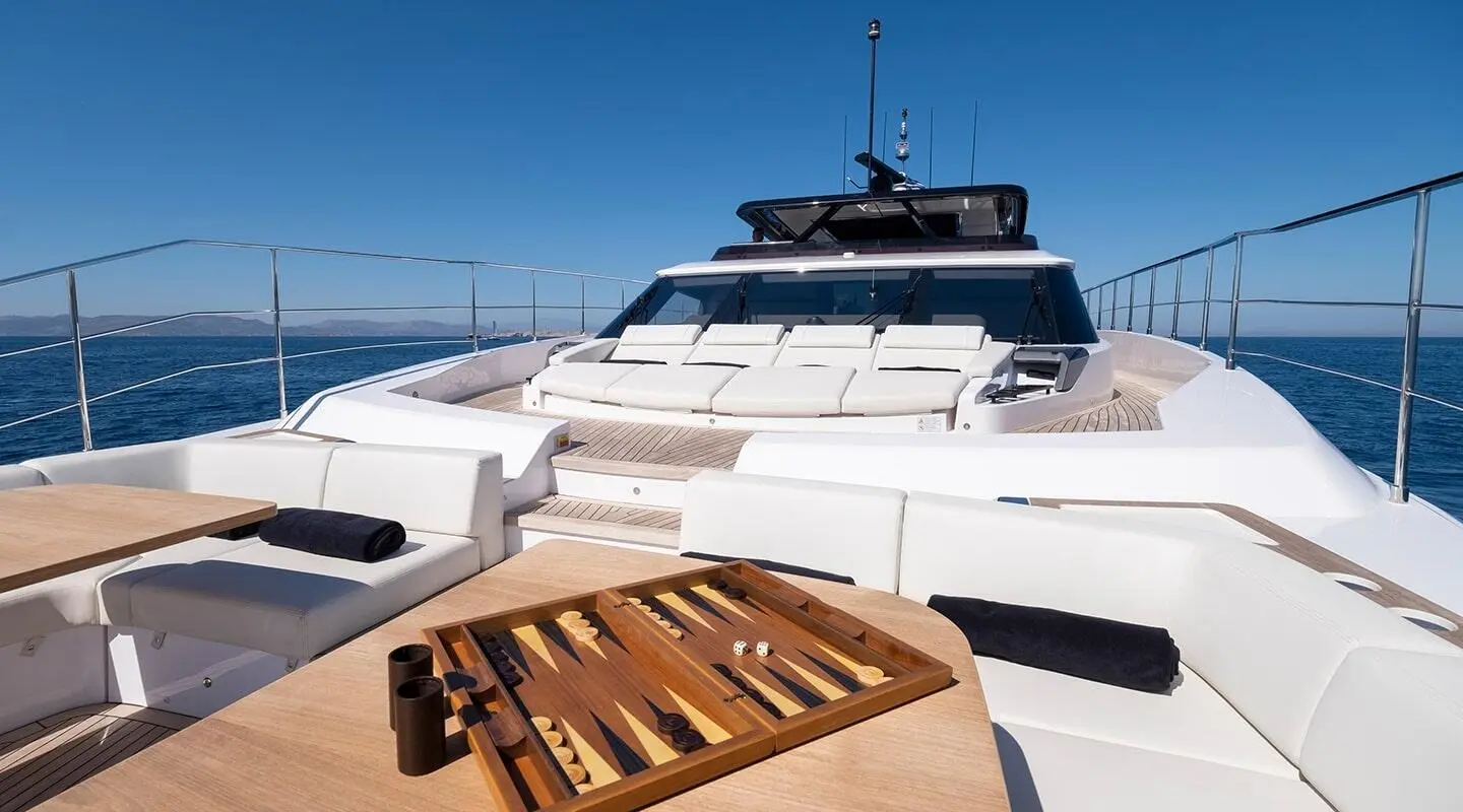 Spica luxury yacht bow deck with white lounge seating and a wooden backgammon board