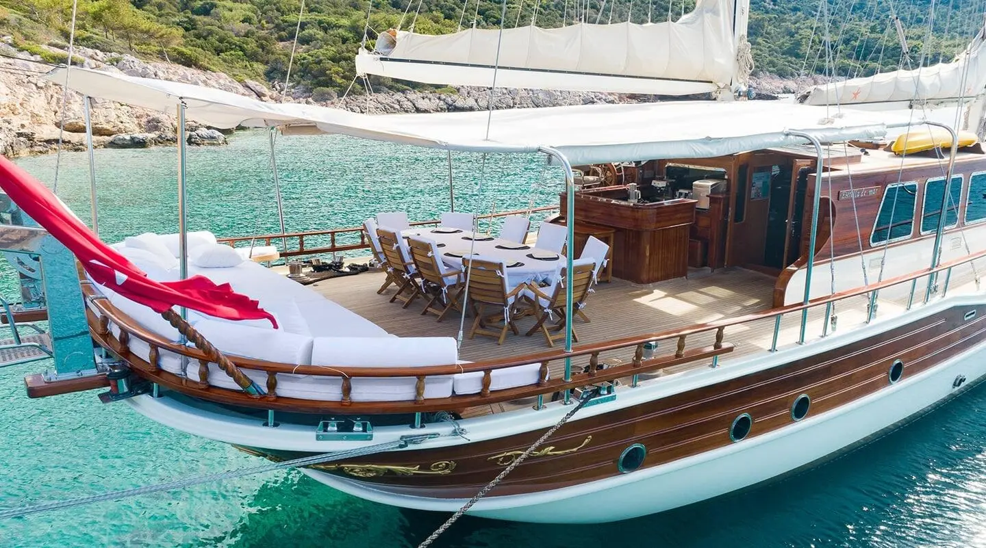 Estrella De Mar yacht anchored near a wooden deck with striped lounge chairs